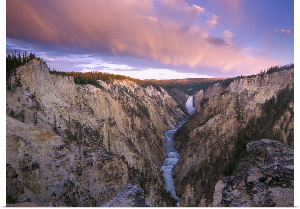 Lower Yellowstone Falls running through a valley in Yellowstone National Park with the sunset hitting the upper cliffs.