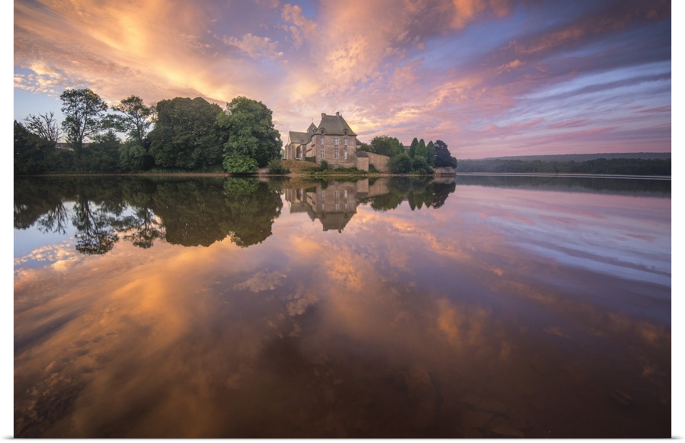 Abbey on the French coast under a pastel sunset sky reflected in the water.