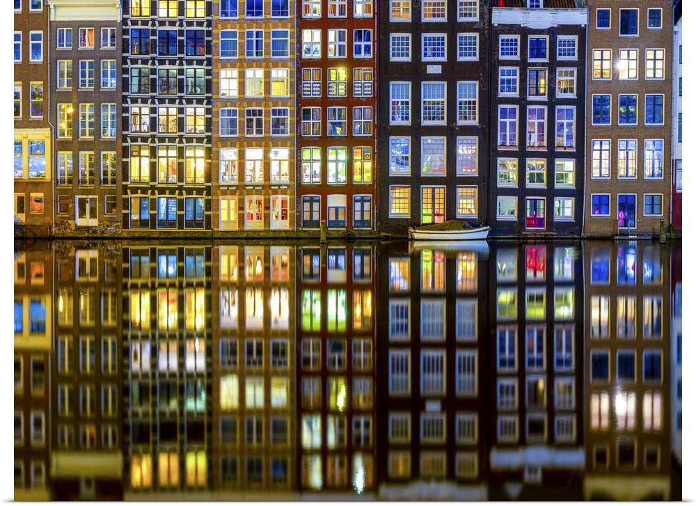 The historic center of Amsterdam with the interiors of the illuminated houses and the reflection of the buildings in the w...