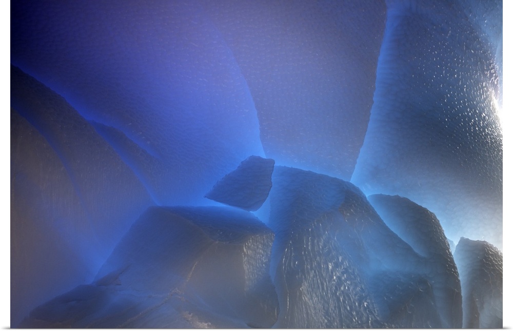 Close up view of ice with light shining through, creating a deep blue glow.