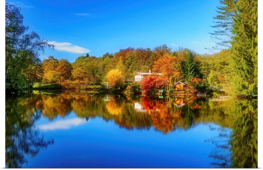 Colorful trees in the fall and a deep blue sky reflected in the calm waters of a lake.