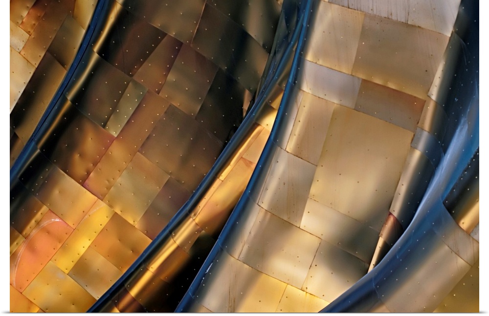 Abstract photograph of a large metal structure reflecting blue and gold light.