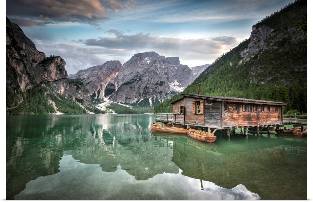 Jade green lake reflecting mountainous valley and cabin.