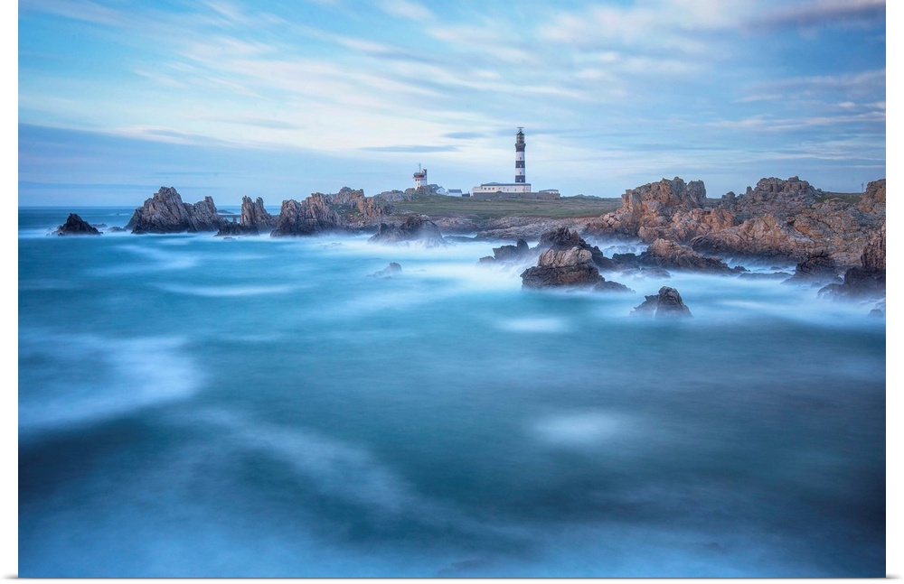 Fine art photo of a lighthouse on a rocky coast with a cloudy sky and deep blue ocean.