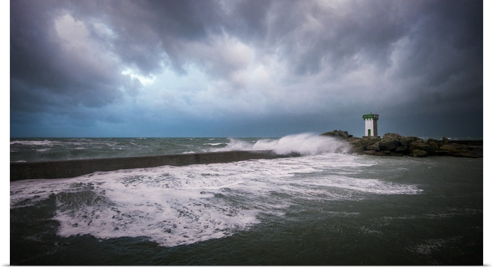 A photograph of the French coast with a lighthouse in the distance under a sky filled with ominous clouds.