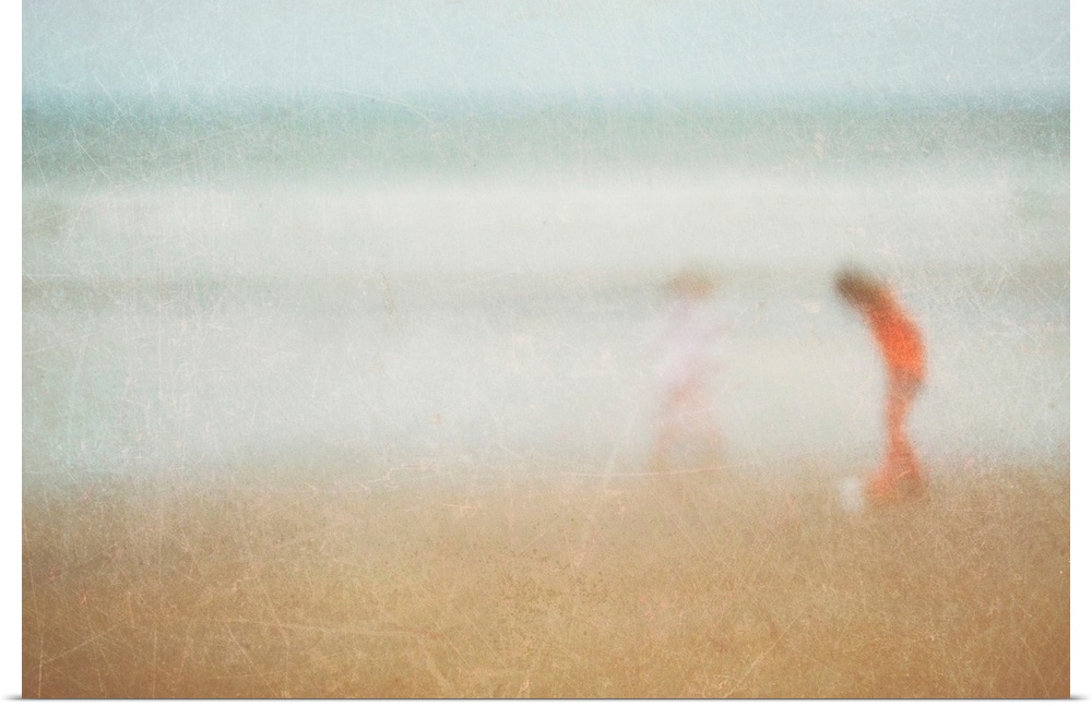 Giant photograph shows two children playing on a sandy beach at the edge of an ocean.  Photographer sets a very soft focus...