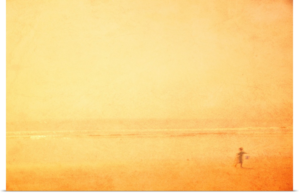 A dreamlike shimmering hazy yellow gold image of a child playing on a beach in the sun on holiday vacation.