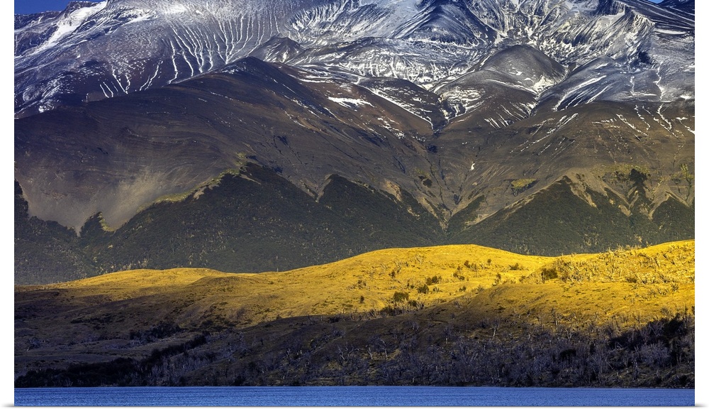 Sunlight on the side of the mountains under the snowy peaks of the Andes in Chile.