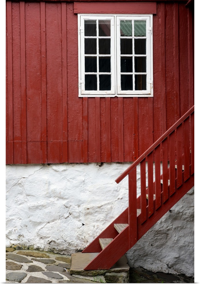 A red staircase against a house with a white framed window.