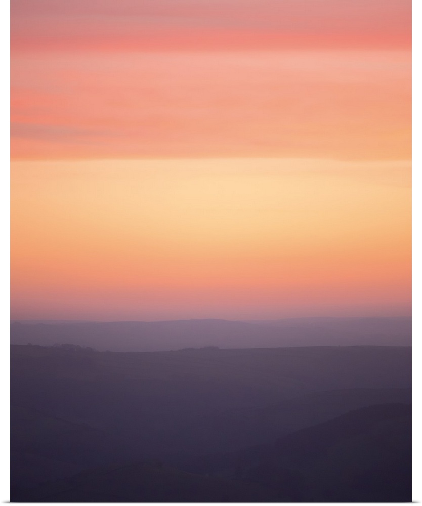 A photograph of a silhouetted hazy landscape under a sunset sky.