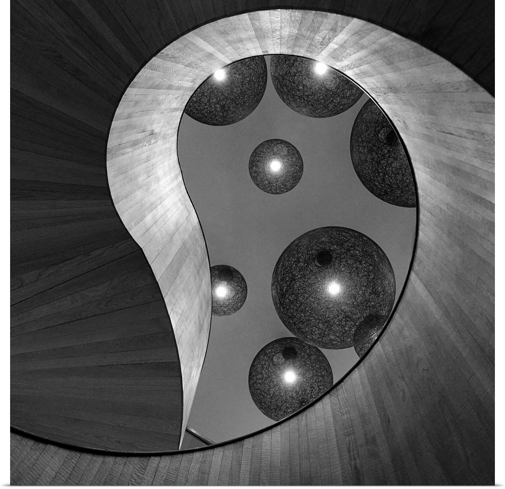 Black and white abstract photograph of large and small spheres hovering around an organic architectural structure.