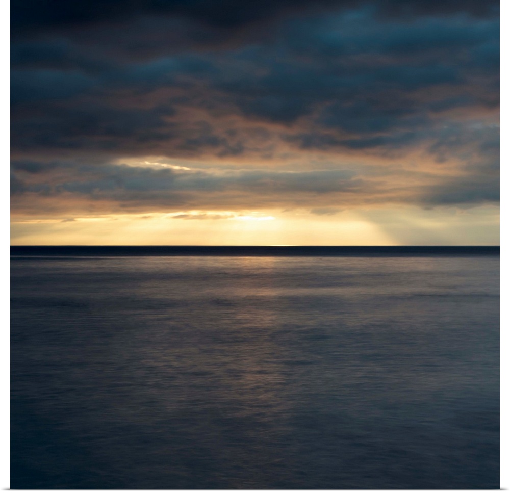 A dramatic dark golden dawn seascape over a still sea.