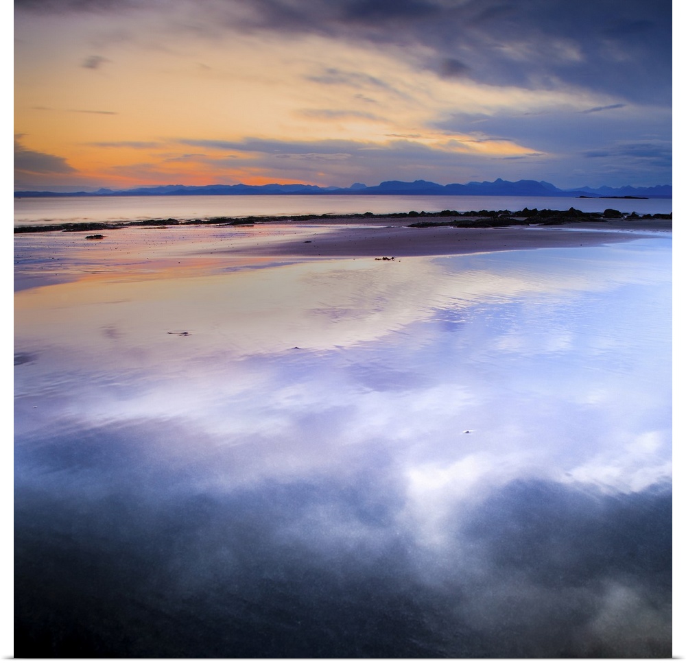 Purple and orange dawn sky with reflections in wet sand.