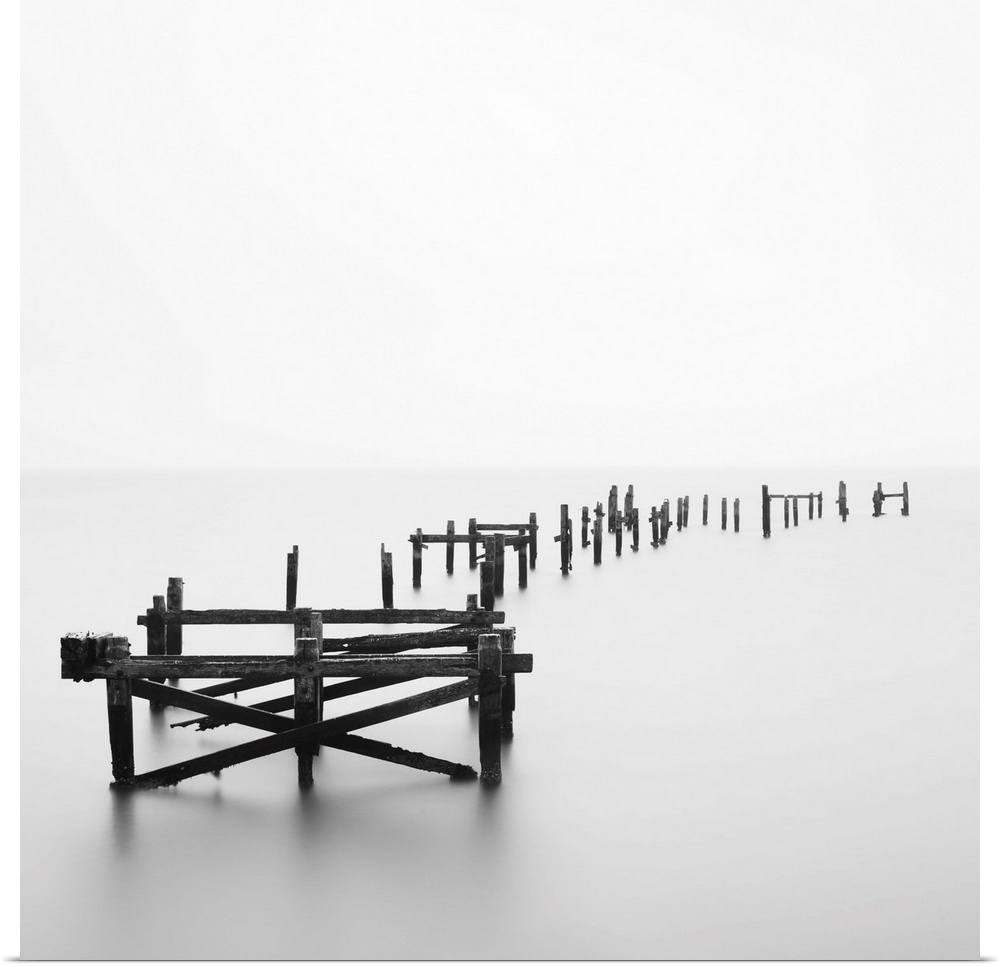 Large photograph focuses on a deteriorating dock sitting alone in a wasteland of fog.