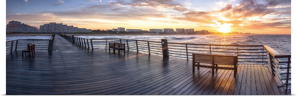 Panoramic sunset view of estacade wood bridge in Saint Jean de Monts city in France, beach and sea with benches.