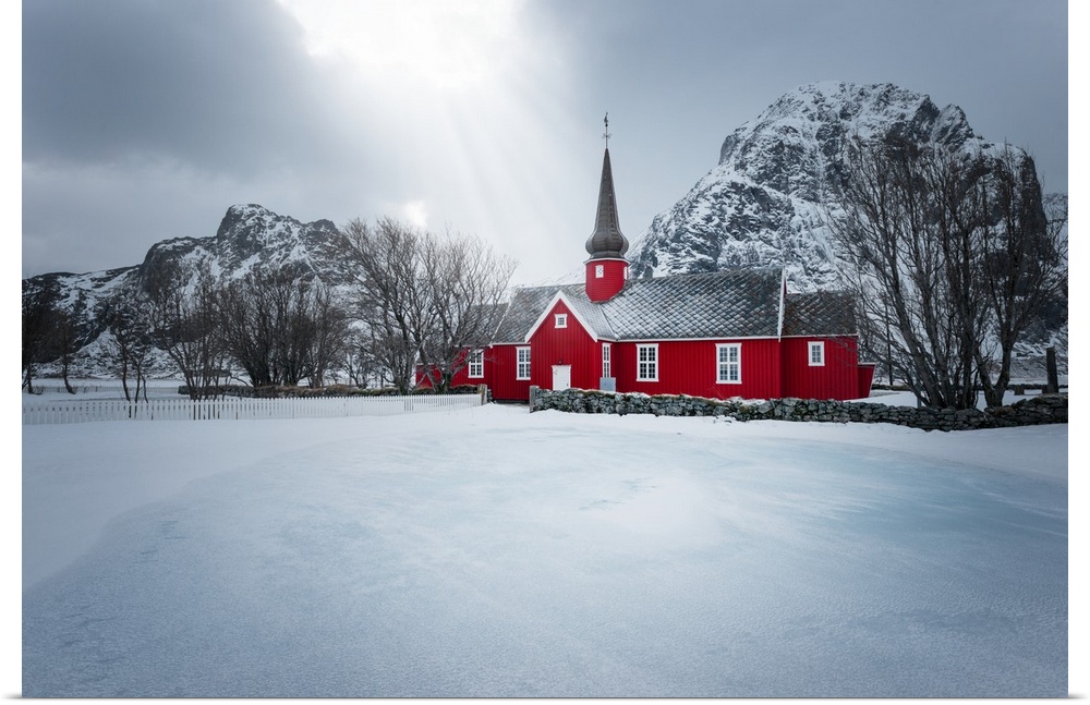 A photograph of red church seen in a wintry landscape.