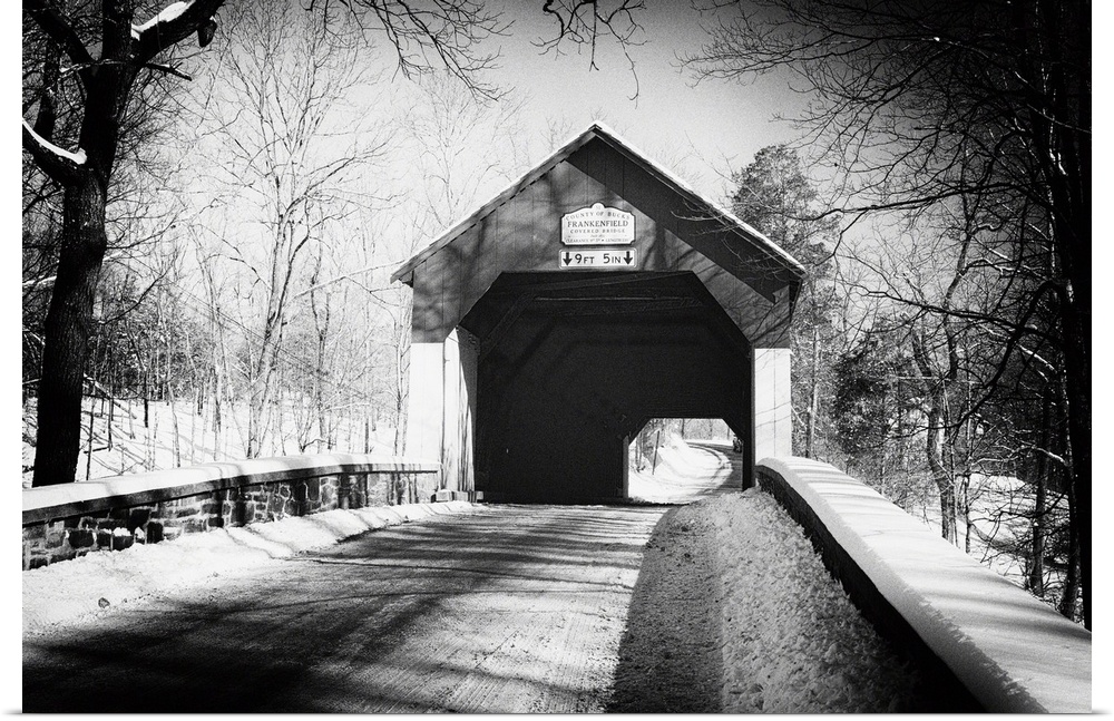 A black and white image of Frankenfield Covered Bridge in Pennsylvania, with a light snowfall.