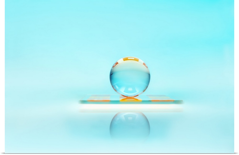 A clear glass sphere resting against a turquoise backdrop.