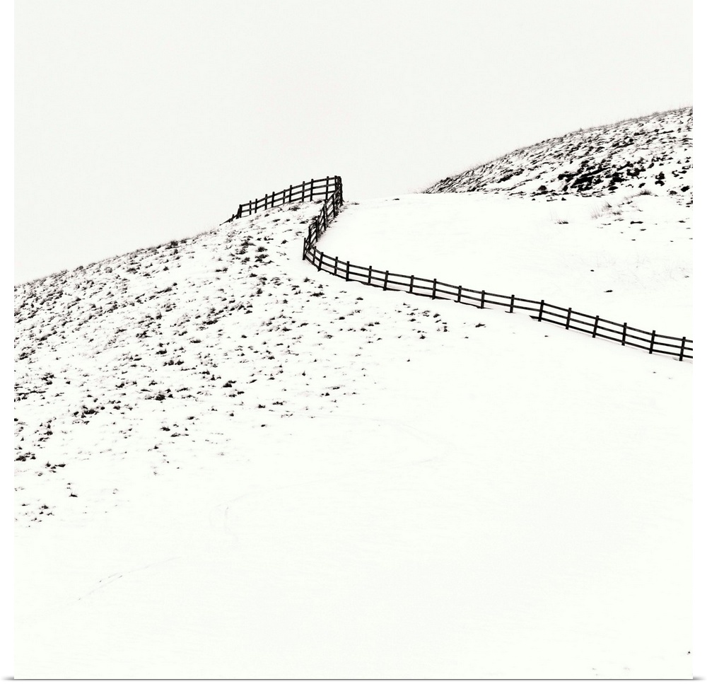 A contemporary minimalist winter landscape showing a curving fence climbing a snow covered hill.
