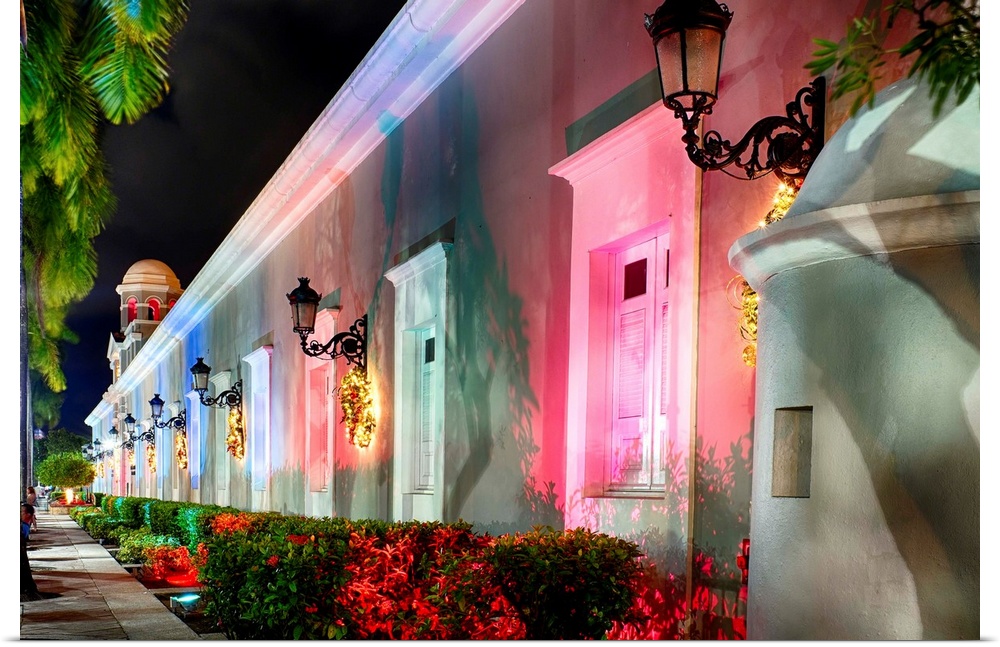The side of a Spanish style building illuminated in varying colors for Christmastime.