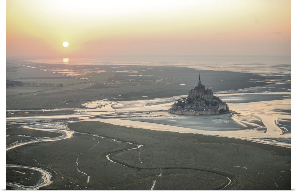 Mont Saint Michel in France at low tide under the setting sun.