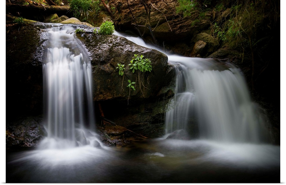 A photograph of a waterfall streaming down rocks in a forest.