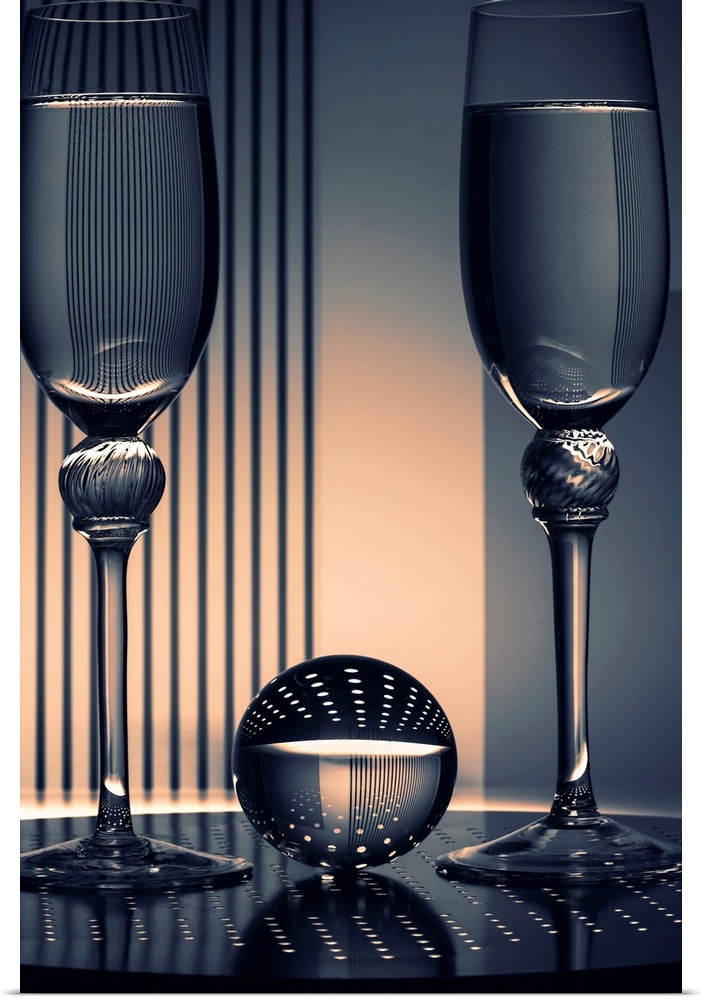 Photograph of a glass ball in between two champagne flutes reflecting all of the shapes and patterns underneath and in the...
