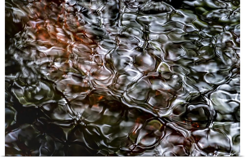A photograph of a close-up of rippled water with a dark brown peering through the surface.