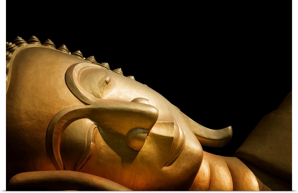 The head of a reclining Buddha in front of a black background