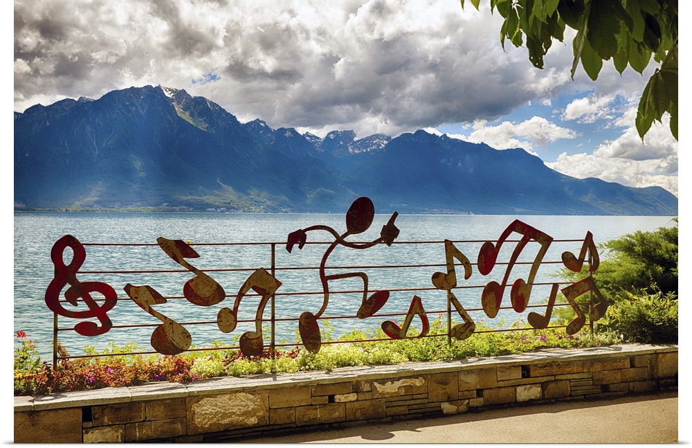 A photograph of a mountain range in the distance from musical notation decorated fence.