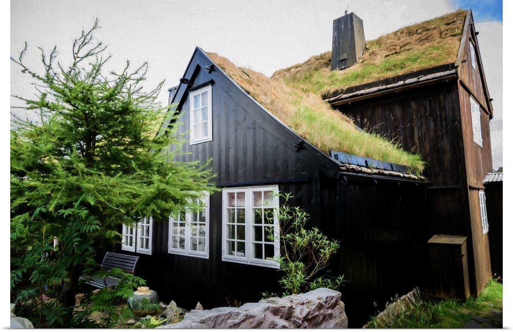 Old house with black walls and a grassy roof.