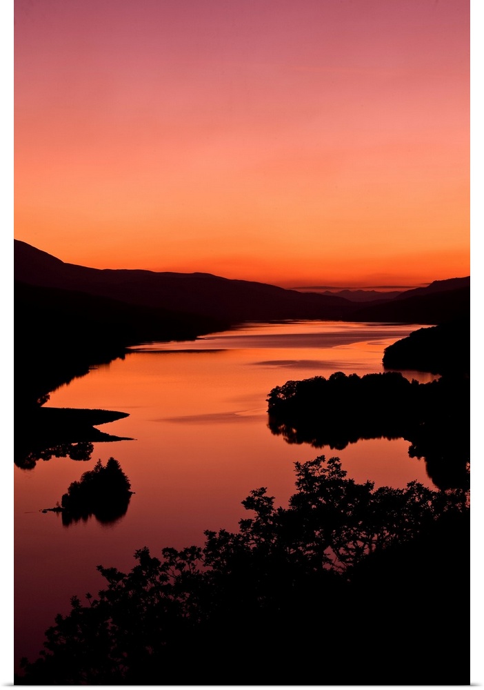 An intense orange sunset landscape view over a loch in Scotland.