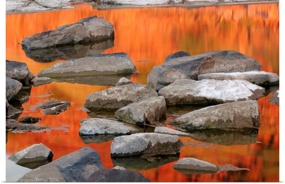 Landscape photograph of a body of orange water with streaking reflections and many rocks, in Mornington Sanctuary, Kimberl...