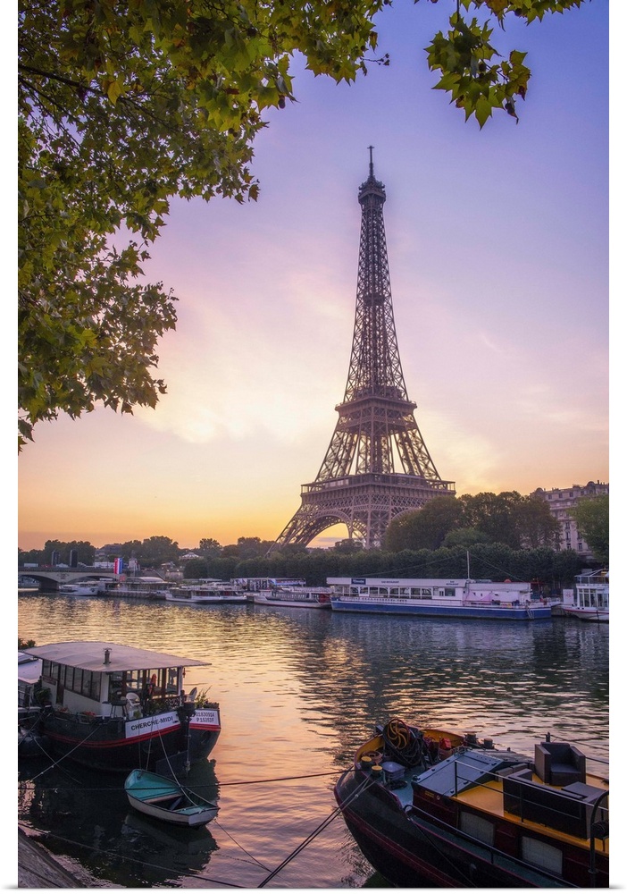 Sunrise on the Eiffel tower on summer morning in Paris with Peniche boats waiting on the side of the river. Some trees aro...