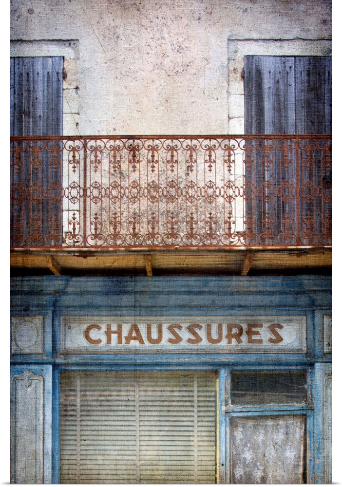 A vintage image of an old faded French shop front in Paris with a wrought iron balcony in blues and neutral tones.