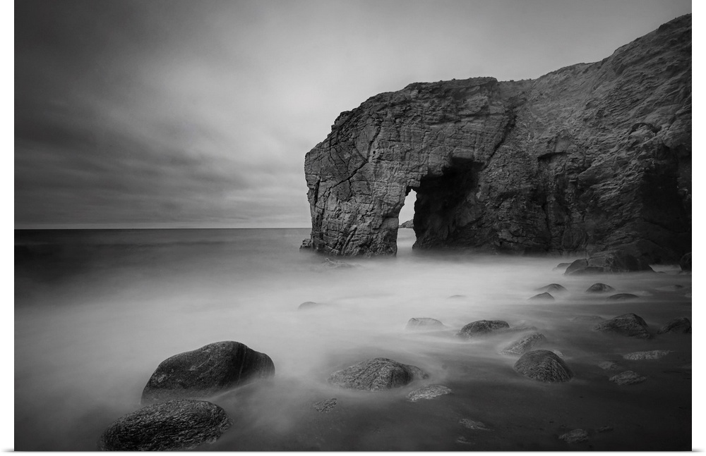 The natural arch rock in Quiberon island in Britany at high tide, a long black and white time exposure, sand beach in Fran...