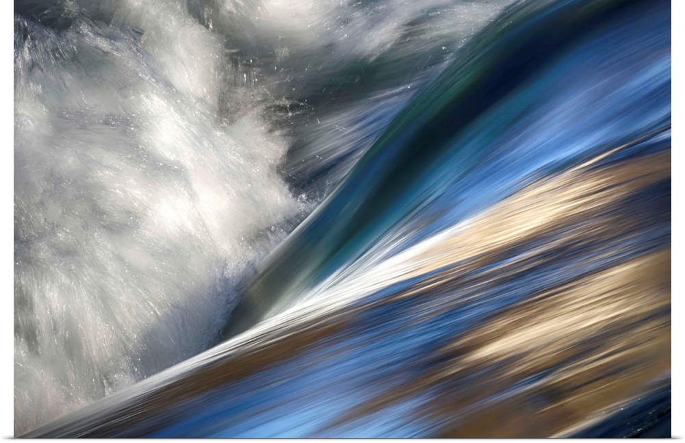 Abstract photo of rushing water with color reflecting off the waves.