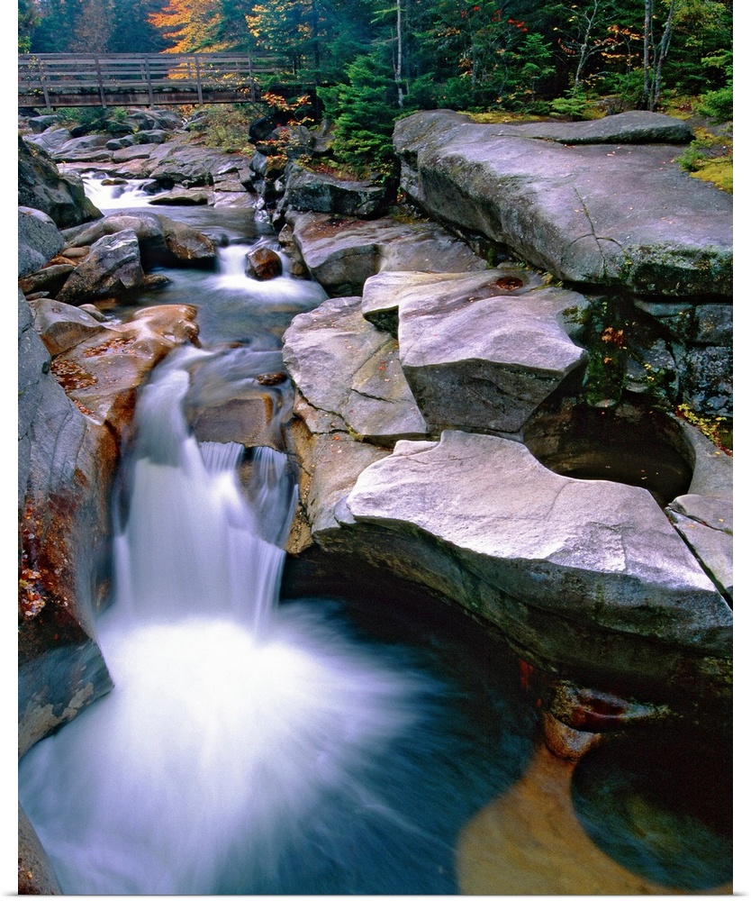 Waterfall on the Ammonoosuc River near Mount Washington, New Hampshire (NH). A wooden bridge and forest are visible in the...