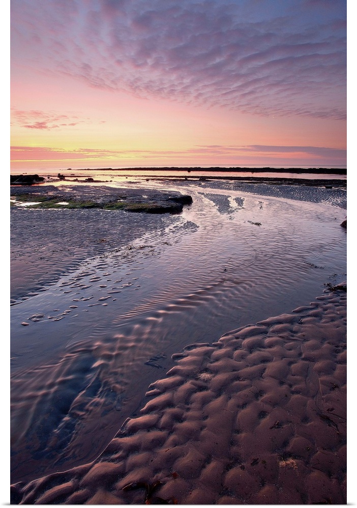 A stunning sunrise with golden light and dramatic clouds over rippled sand patterns.