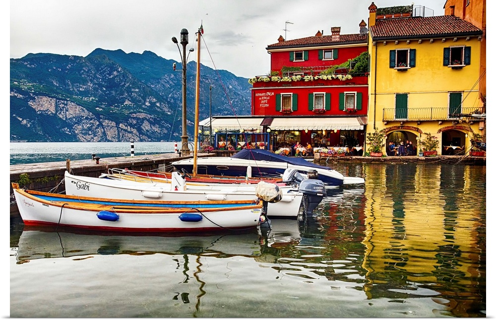 Fine art photo of boats docked in a harbor near brightly painted houses in Italy.