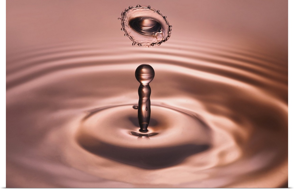 A macro photograph of a water droplet rising up from a small splash.