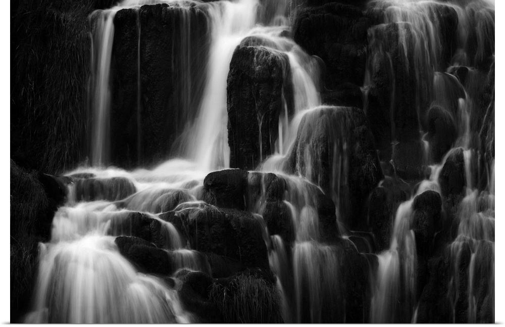 Fine art photo of a waterfall over several round rocks in black and white.