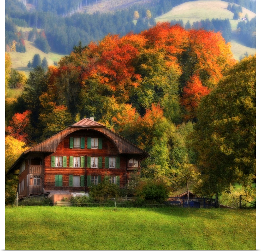 Photograph of cabin at the bottom of a foothill with autumn colored forest in the background.