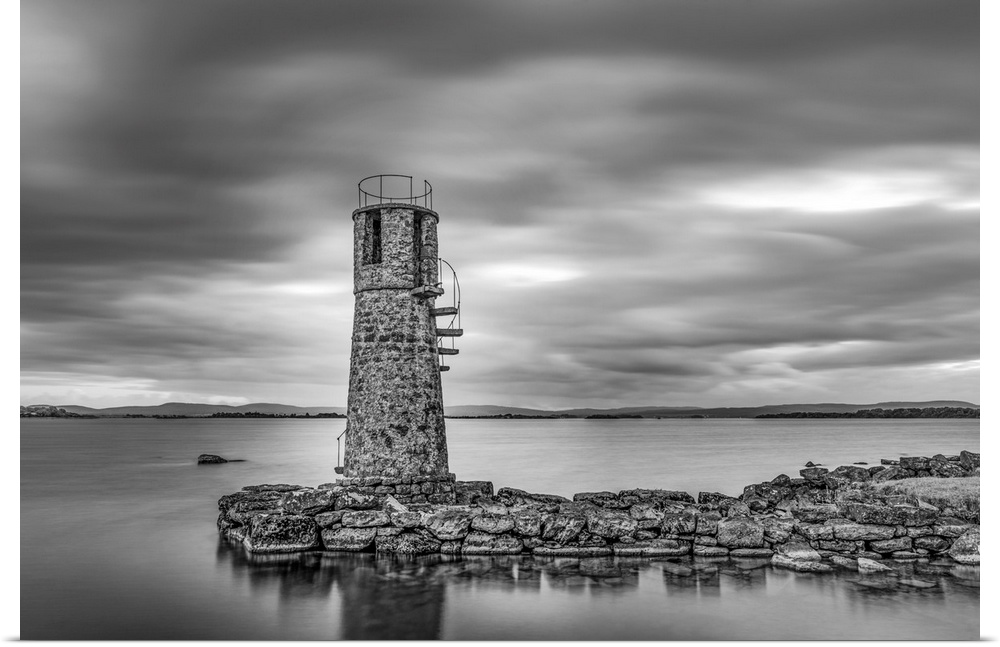 Black and white photo of an old lighthouse by a lake