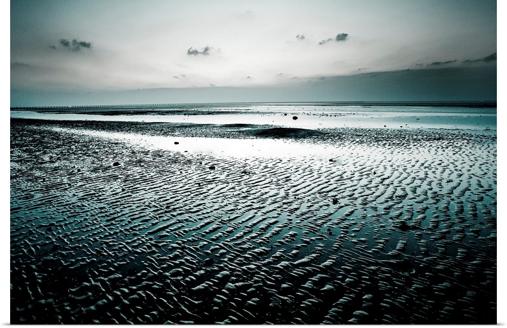 Big, landscape, fine art photograph of a wet, empty beach, surrounded by darkness beneath a gray sky.