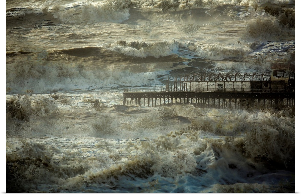 Repeated rough ocean waves crashing all around a pier.