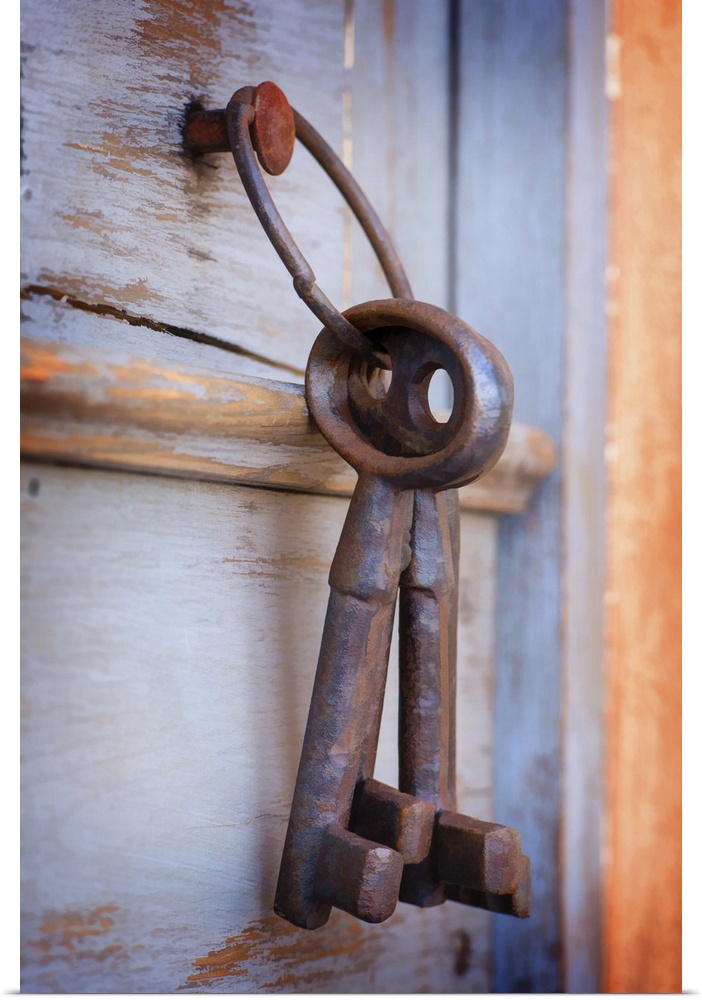 A photograph of a set of large rustic keys hanging on a wooden door.