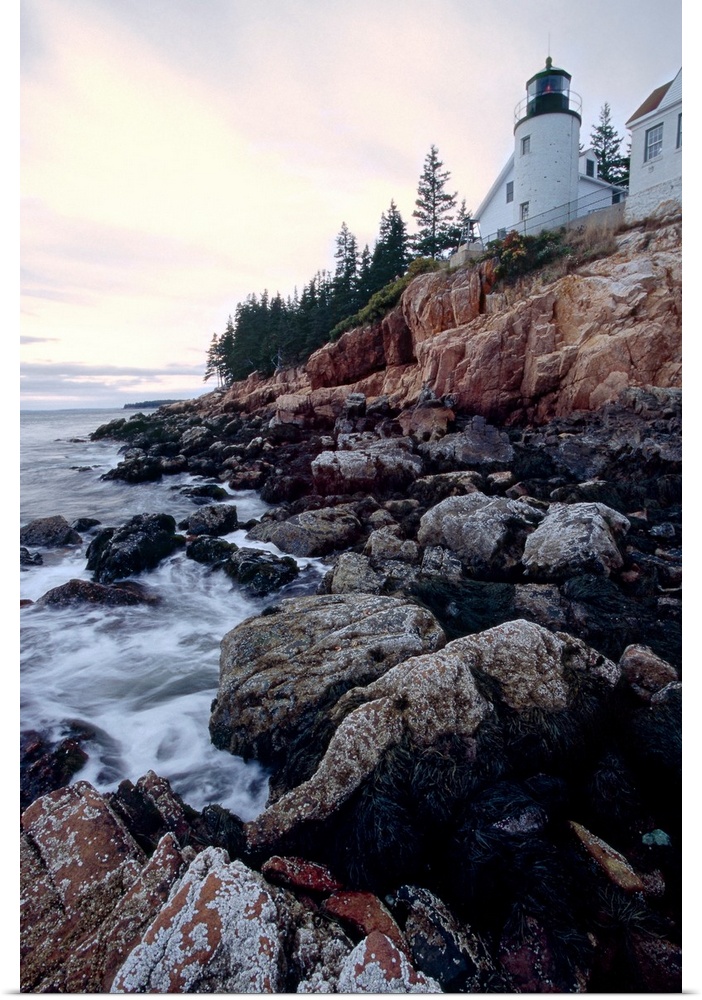 Low angle view of the bass harbor head lighthouse that sits atop a rocky cliff.