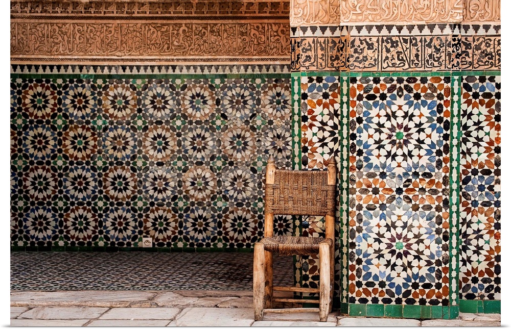 Photograph of a wooden chair with a woven seat and back against beautifully tiled exterior walls.