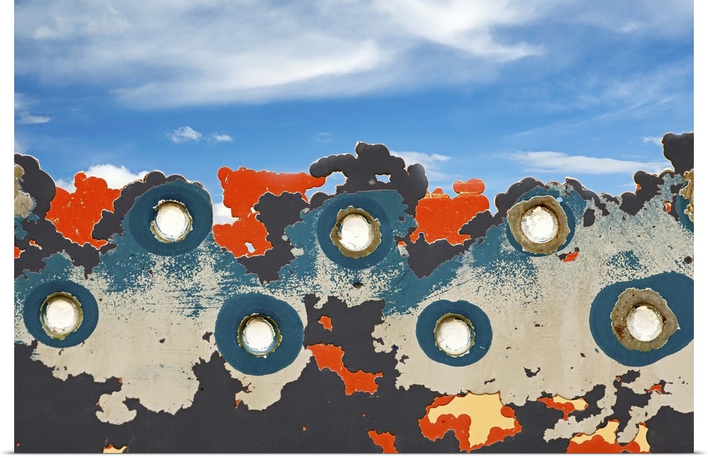 Abstract image created by rivets and peeling paint against the blue sky.